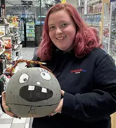 Lakeside Trading team member holding a painted Halloween pumpkin